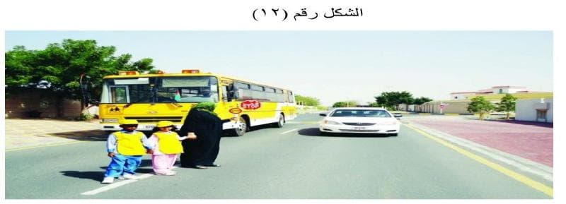 طفلان يعبران الطريق أمام حافلة مدرسية بينما تقترب مركبة